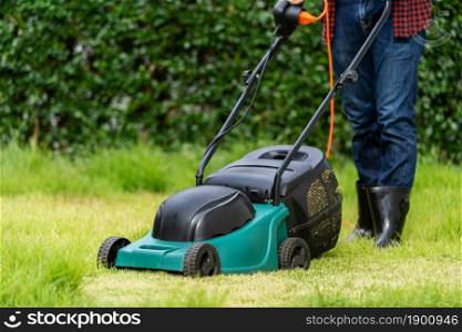 worker using a lawn mower cutting grass at home