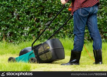 worker using a lawn mower cutting grass at home