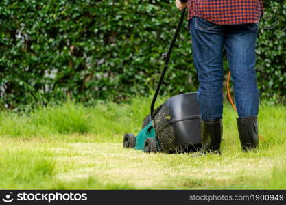 worker using a lawn mower cutting grass at home