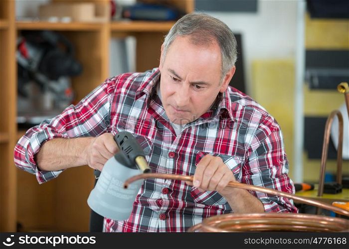 worker using blowtorch for soldering copper fittings