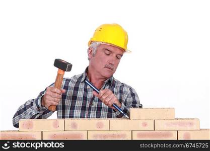 Worker using hammer and chisel on wall