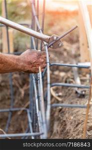 Worker Using Tools To Bend Steel Rebar At Construction Site.