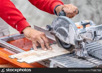 Worker Using Wet Tile Saw to Cut Wall Tile At Construction Site.