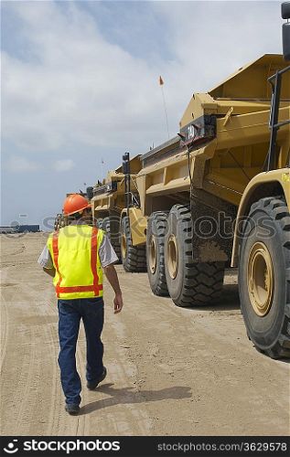 Worker walking near trucks at landfill site