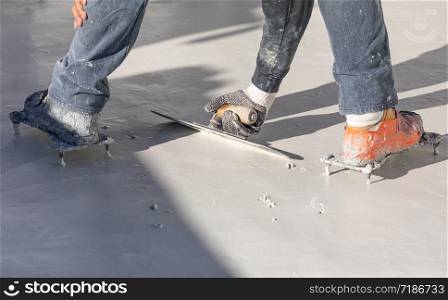 Worker Wearing Spiked Shoes Smoothing Wet Pool Plaster With Trowel.