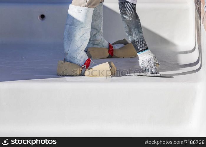 Worker Wearing Sponges On Shoes Smoothing Wet Pool Plaster With Trowel.