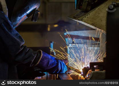 worker welding automotive part in car factory