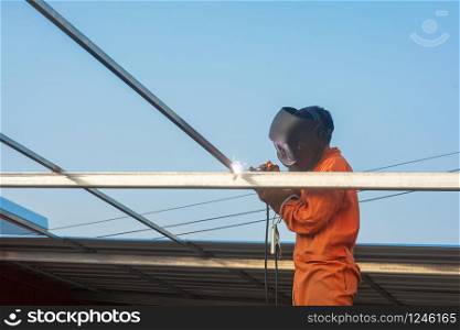 Worker welding in orange work clothes welding For roof truss