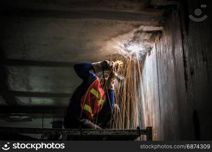 worker welding metal with sparks in construction site