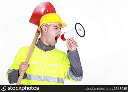 Worker with a spade screaming into a bullhorn