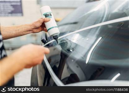 Worker with polishing machine restores rear window of the car. Auto detailing on carwash service. Worker polishing rear window of the car