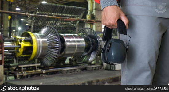 Worker with protective headphone. Worker with protective headphone at man hands at industrial factory