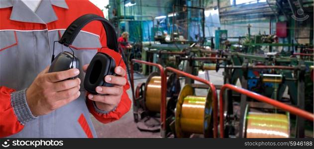 Worker with protective headphone. Worker with protective headphone at man hands at industrial factory