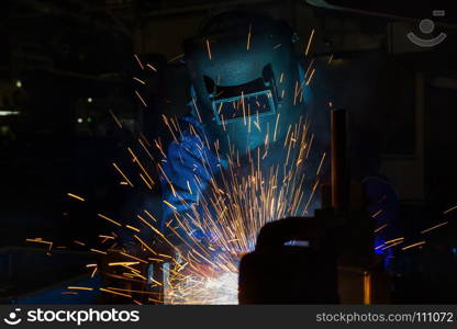 Worker with protective mask welding automotive part in factory