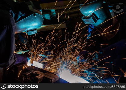 worker with protective mask welding metal in automotive assembly factory.