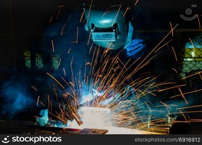 worker with protective mask welding metal in car factory