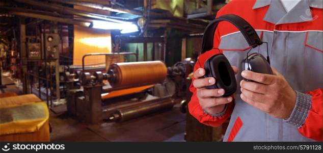 Worker . Worker with protective headphone at man hands at industrial factory