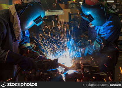 Workers are welding steel part in factory