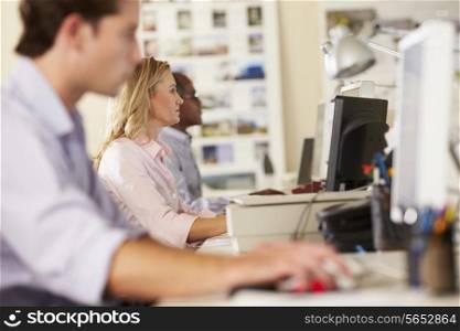 Workers At Desks In Busy Creative Office