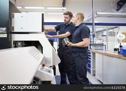 Workers checking control panel in engineering factory