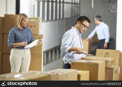 Workers Checking Goods On Belt In Distribution Warehouse