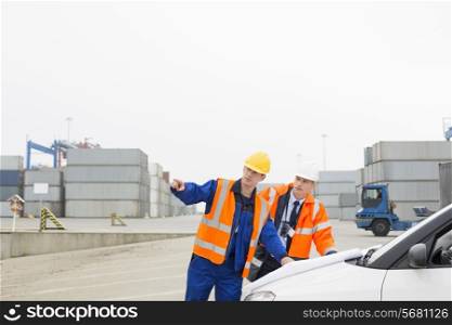 Workers discussing over blueprint in shipping yard