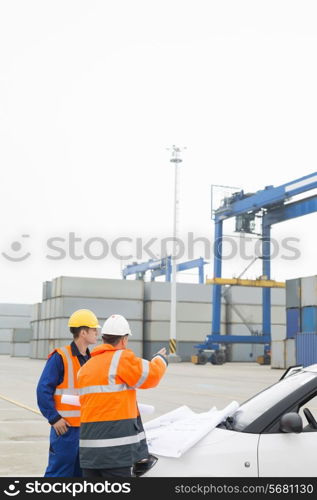 Workers discussing over blueprint in shipping yard