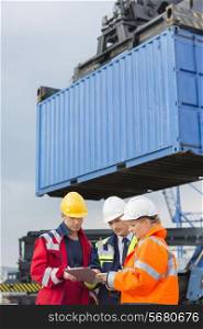Workers discussing over clipboard in shipping yard