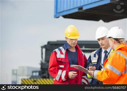 Workers discussing over clipboard in shipping yard