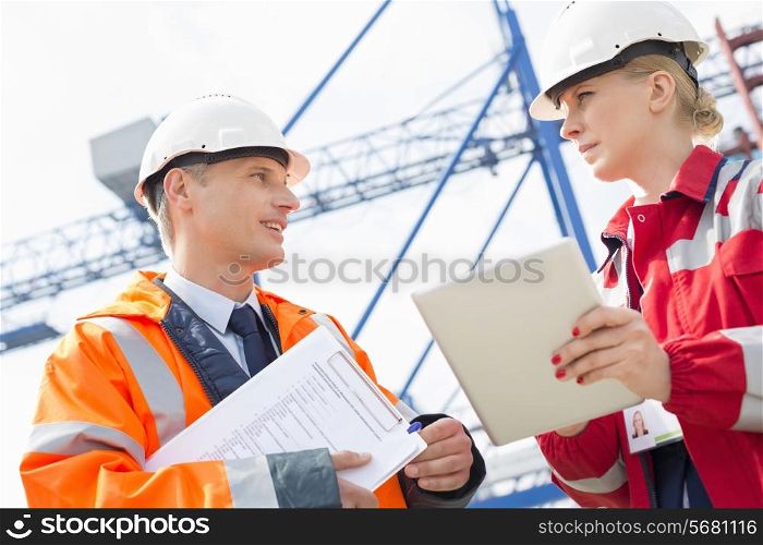 Workers discussing over tablet computer in shipping yard