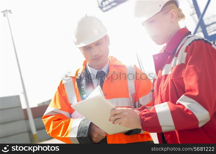 Workers discussing over tablet computer in shipping yard