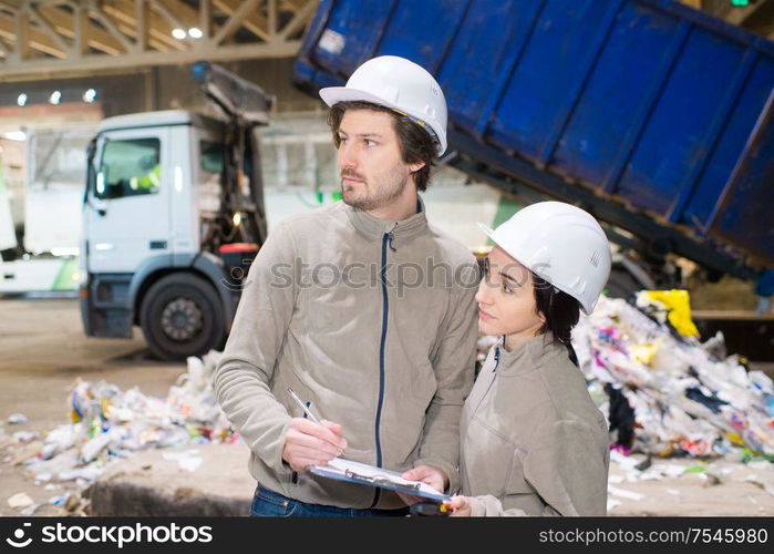 workers in a recycle center lorry tipping in background