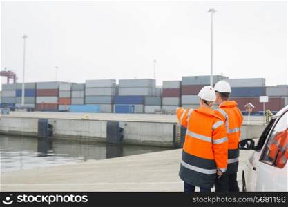 Workers in protective clothing examining cargo in shipping yard