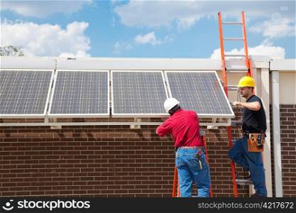 Workers installing solar panels on the side of a building. Wide angle view with room for text.