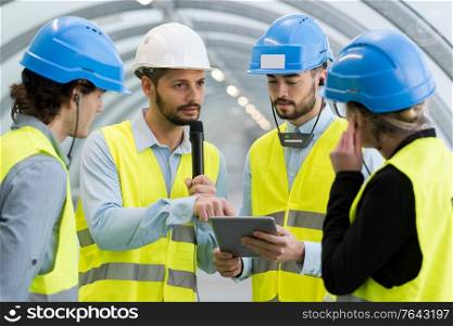 workers looking at tablet and listening to speaker through earphones
