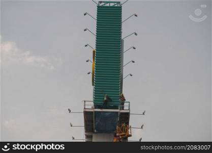 Workers on a truck mounted crane is repairing a large billboard.