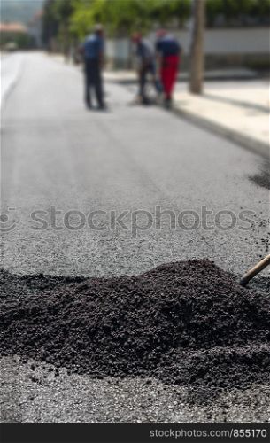 Workers on new road. Heap with asphalt.