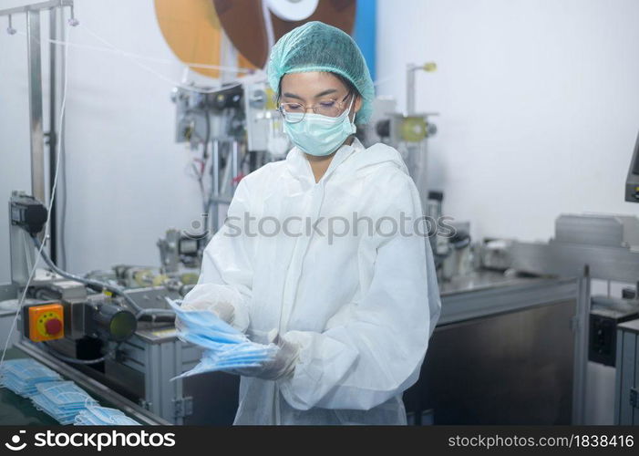 Workers producing surgical mask in modern factory, Covid-19 protection and medical concept.