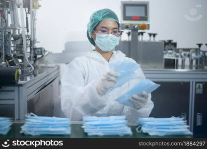 Workers producing surgical mask in modern factory, Covid-19 protection and medical concept.