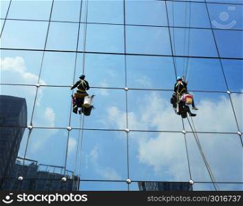 Workers washing windows of the modern skyscraper office building.