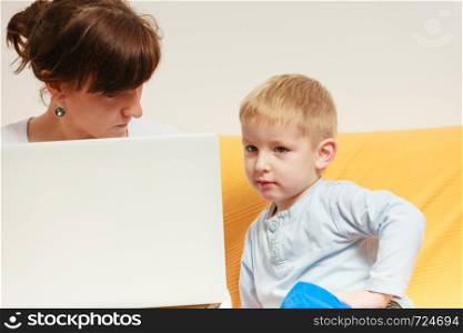 Working at home problems concept. Mother working and using laptop her little boy disturbing. Mother working using laptop, little boy disturbing