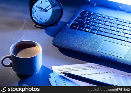 working at night, laptop with documents and cup of coffee on table