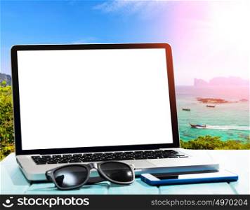 working by the seaside. Modern laptop on blue wooden table with blank screen at tropical beach