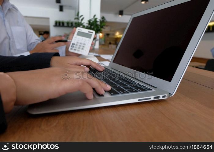 Working by using a laptop computer on wooden table. Hands typing on a keyboard.technology e-commerce