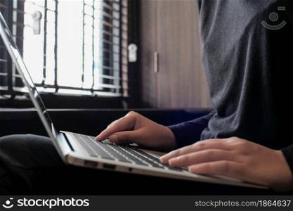 Working by using a laptop computer on wooden table. Hands typing on keyboard