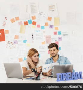 working colleagues looking paper workplace with laptops stationery nameplate