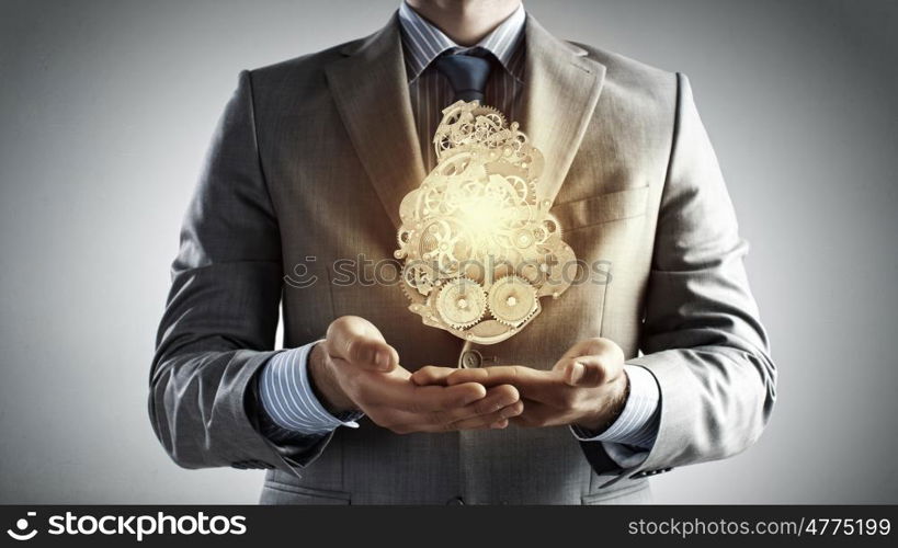 Working gear mechanism. Close up of businessman in suit holding metal gears in hands