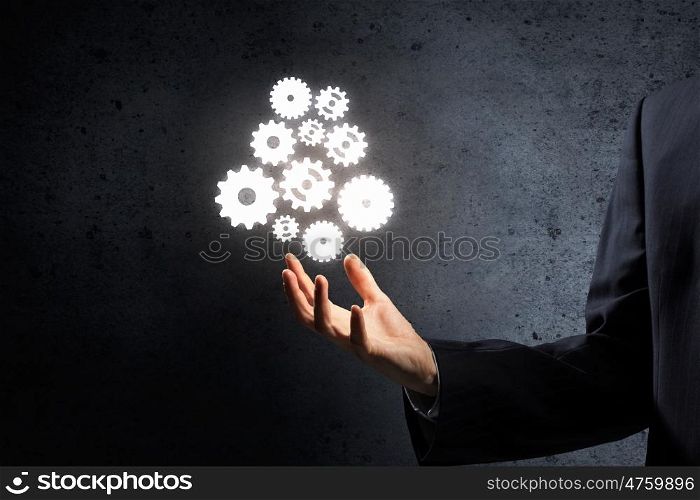 Working in collaboration. Businessman hand holding gear mechanism as teamwork concept