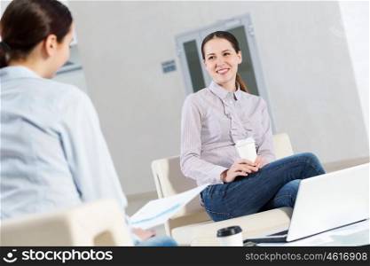 Working in cooperation. Two young women sitting at office having conversation