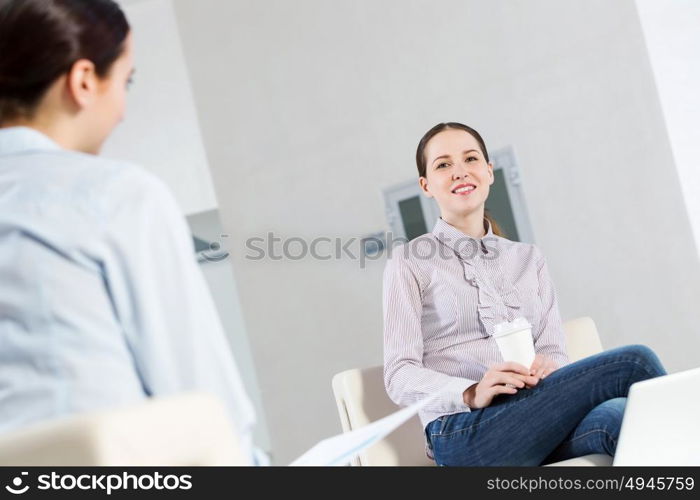 Working in cooperation. Two young women sitting at office having conversation